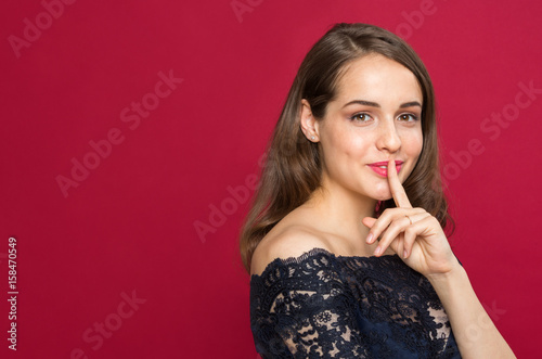 Beautiful girl looking at camera and holding finger near mouth