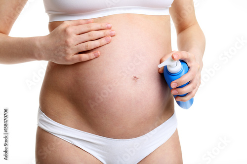 Pregnant woman with anit stretch marks cream over white background © Kalim