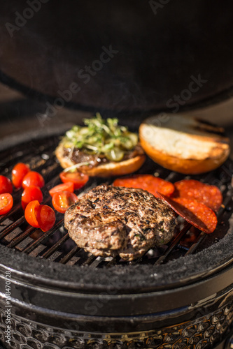 Delicious cheeseburger with tomatoes cooking on hot flaming grill. Barbecue. Restaurant 