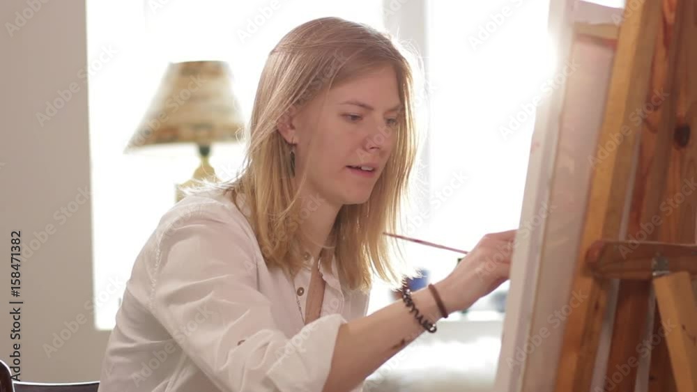 Woman artist painting watercolor paints sitting by the window Woman artist painting watercolor paints sitting by the window