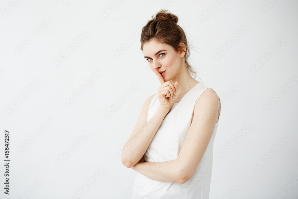 Portrait of young beautiful girl showing keep silence looking at camera over white background.