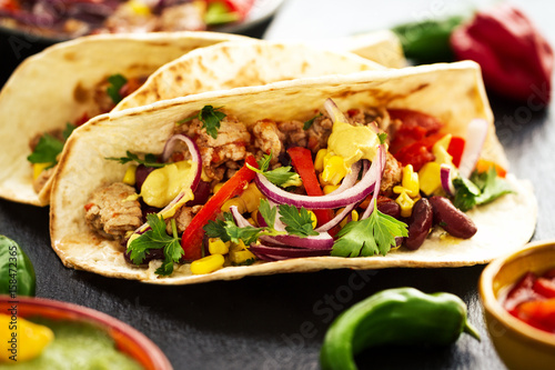 Beautiful tasty appetizing traditional mexican food tacos with meat and vegetables on black slate. Closeup.