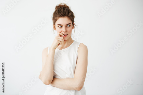 Portrait of young beautiful girl smiling thinking dreaming touching her chin over white background.