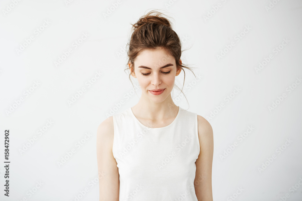 Portrait of young beautiful brunette girl smiling looking down over white background. Portrait of young beautiful brunette girl smiling looking down over white background.