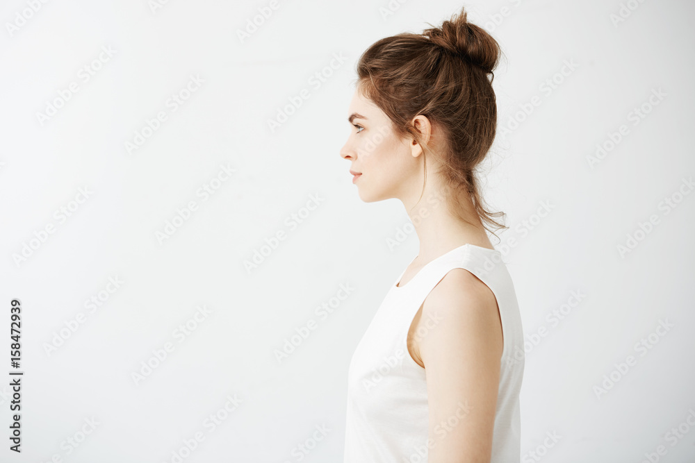 Portrait of young beautiful brunette girl with bun in profile smiling over white background. Portrait of young beautiful brunette girl with bun in profile smiling over white background.