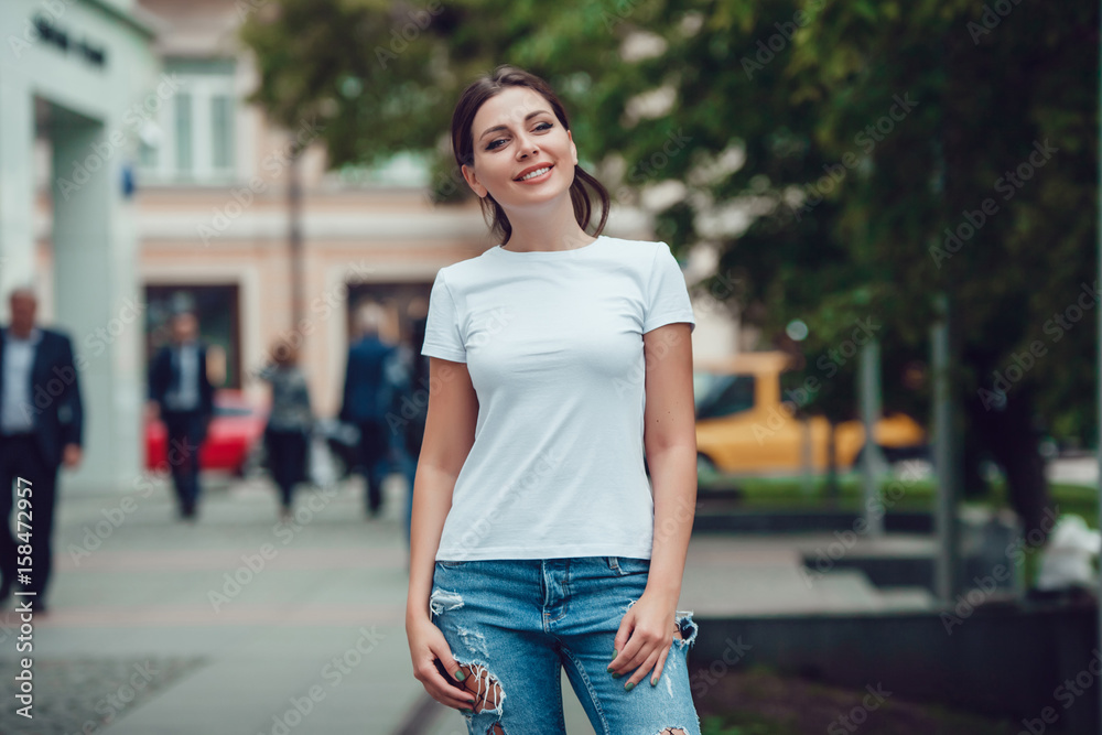 Attractive girl in a white T-shirt on the street. Mock-up.