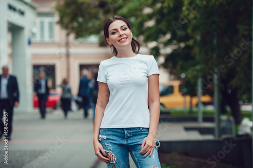 Attractive girl in a white T-shirt on the street. Mock-up. © kanashkin