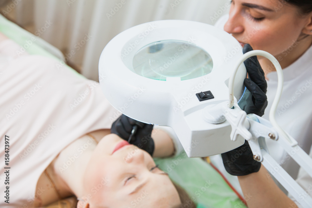 Cosmetologist applying permanent makeup on lips Cosmetologist applying permanent makeup on lips