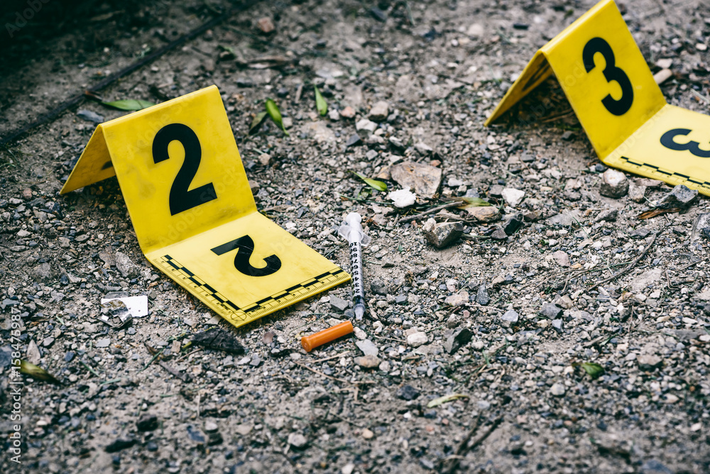 Crime scene marker next to tossed syringe on the ground Stock Photo ...
