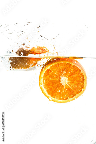 Fototapeta Naklejka Na Ścianę i Meble -  orange halves falling into water on white background