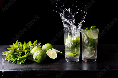 Mojito traditional beach refreshing cocktail alcohol drink in glass with splash, bar preparation soda water, lime, mint leaves, sugar, and rum