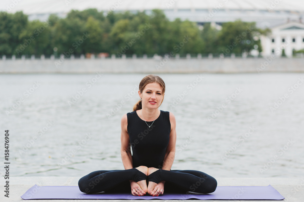 Fototapeta premium a young woman practicing yoga asanas in the city on the waterfront