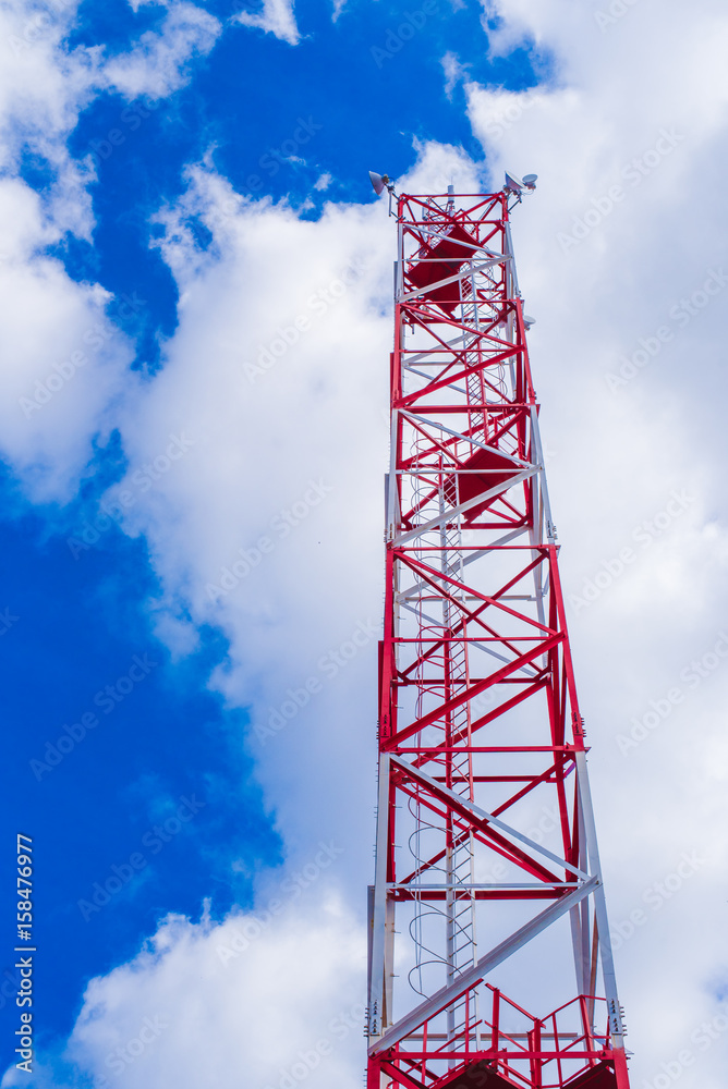 Mobile phone communication antenna tower with satellite dish on blue sky background with sun ray flair., Telecommunication tower