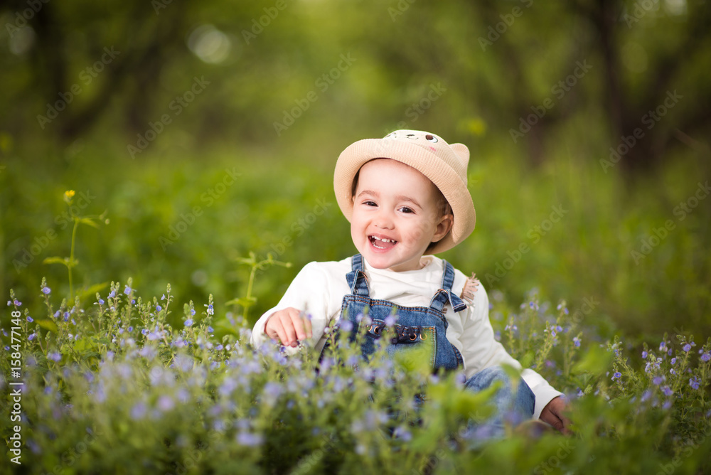 A little girl sitting in the garden and sniffs flowers, emotions, joy A little girl sitting in the garden and sniffs flowers, emotions, joy