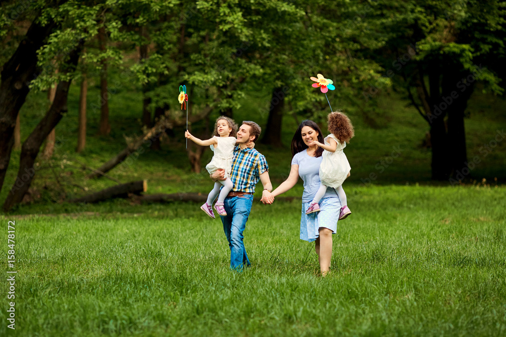 Happy family walking playing in summer park.