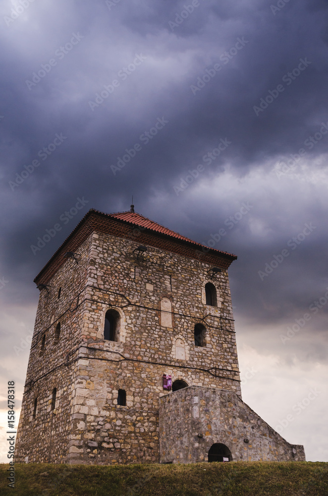Old tower on the hill above the city under the cloudy sky
