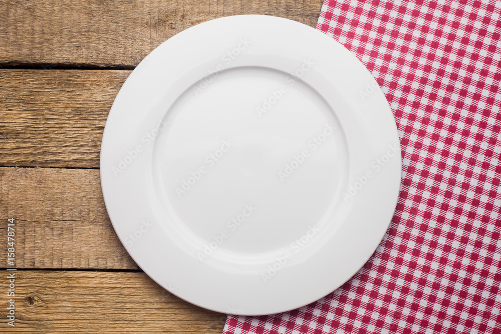 empty plate on a wooden background, a napkin in a red and white cage empty plate on a wooden background, a napkin in a red and white cage