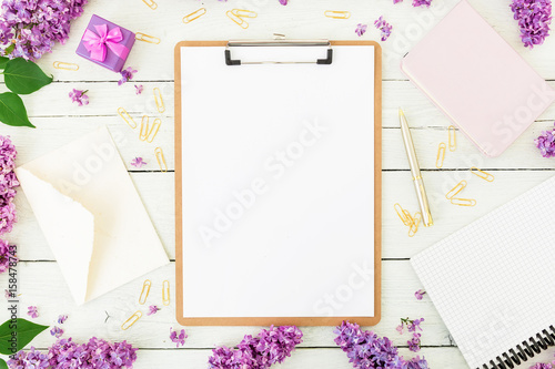 Minimalistic workspace with clipboard, envelope, lilac and accessories on white background. Freelancer or blogger concept. Flat lay, top view.