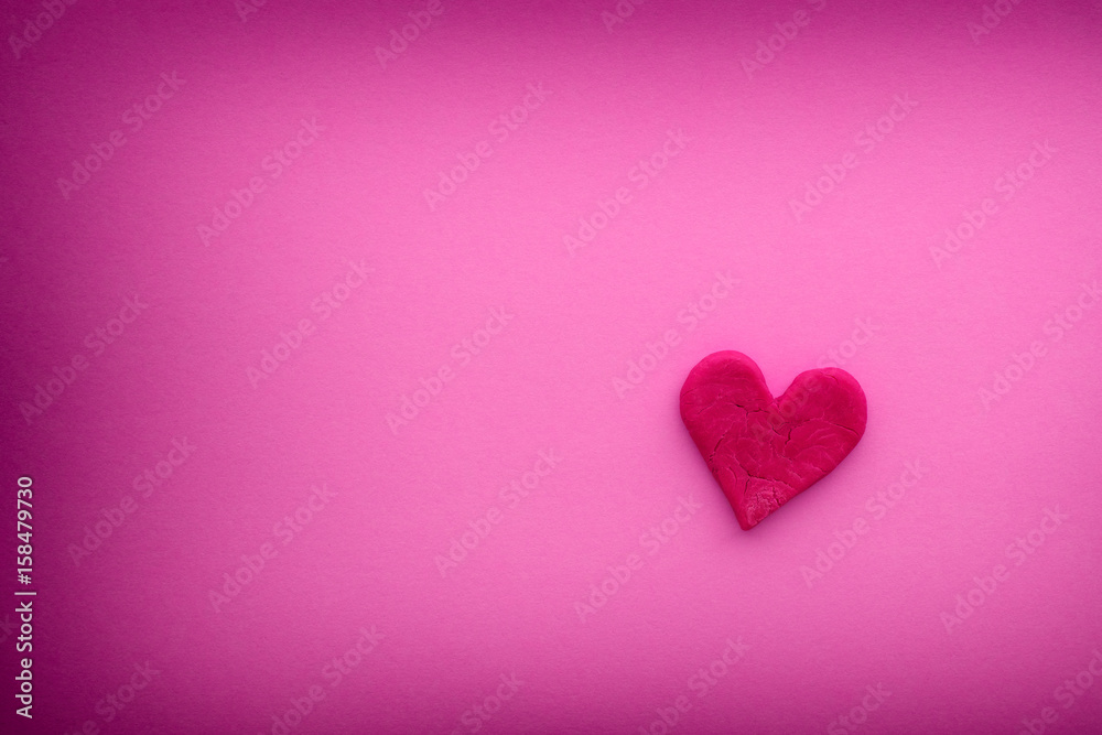 Red heart with small cracks on a pink background