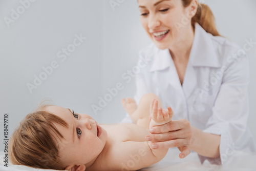 Cute distinguished pediatrician smiling during the procedure