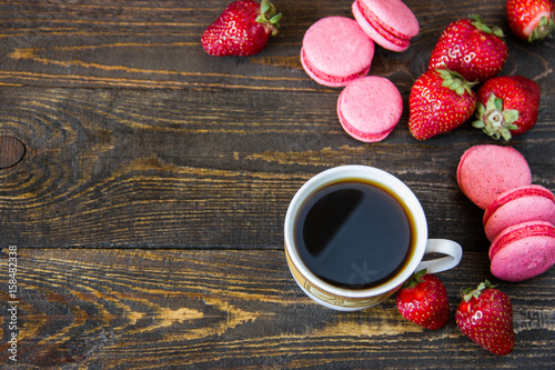 cup of coffee and strawberry macaroons on a wooden table