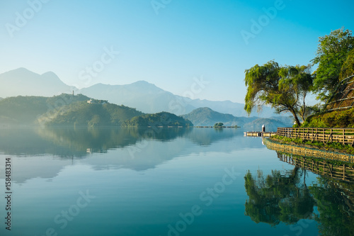 Reflection of trees, mountains, and islands on the clear water lake, sun moon lake. The lake has very clear water and can reflect trees and mountains on its surface. 