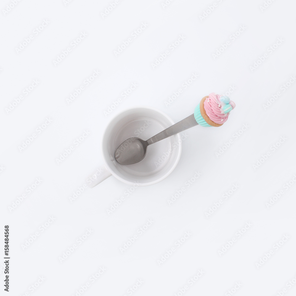 White cup with a spoon and cookies on a white background White cup with a spoon and cookies on a white background