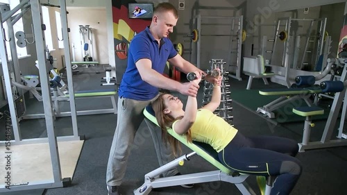 Beautiful woman at the gym exercising with her trainer photo