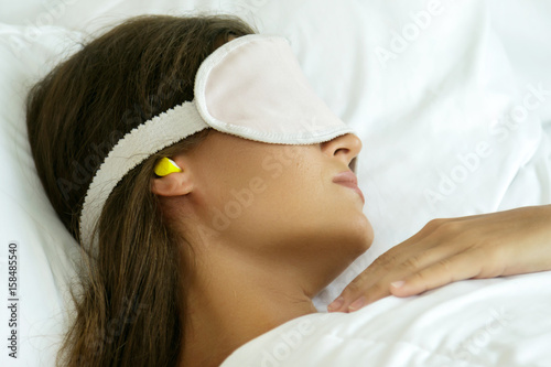 Woman is wearing eye mask and using earplugs