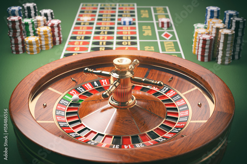 Casino roulette wheel with casino chips on green table. Gambling background.