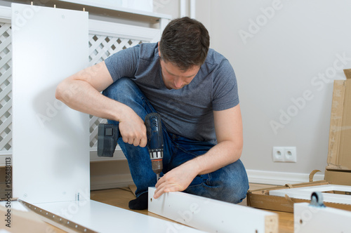 Handsome man assembling furniture at home.