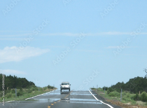 Mirage on highway with car on a hot desert day in July in Arizona, United States.