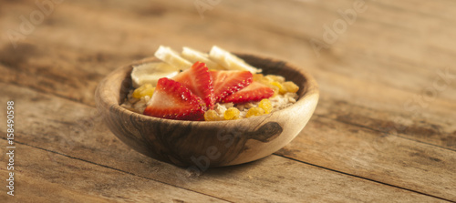 oatmeal porridge with strawberry and banana in wood bowl