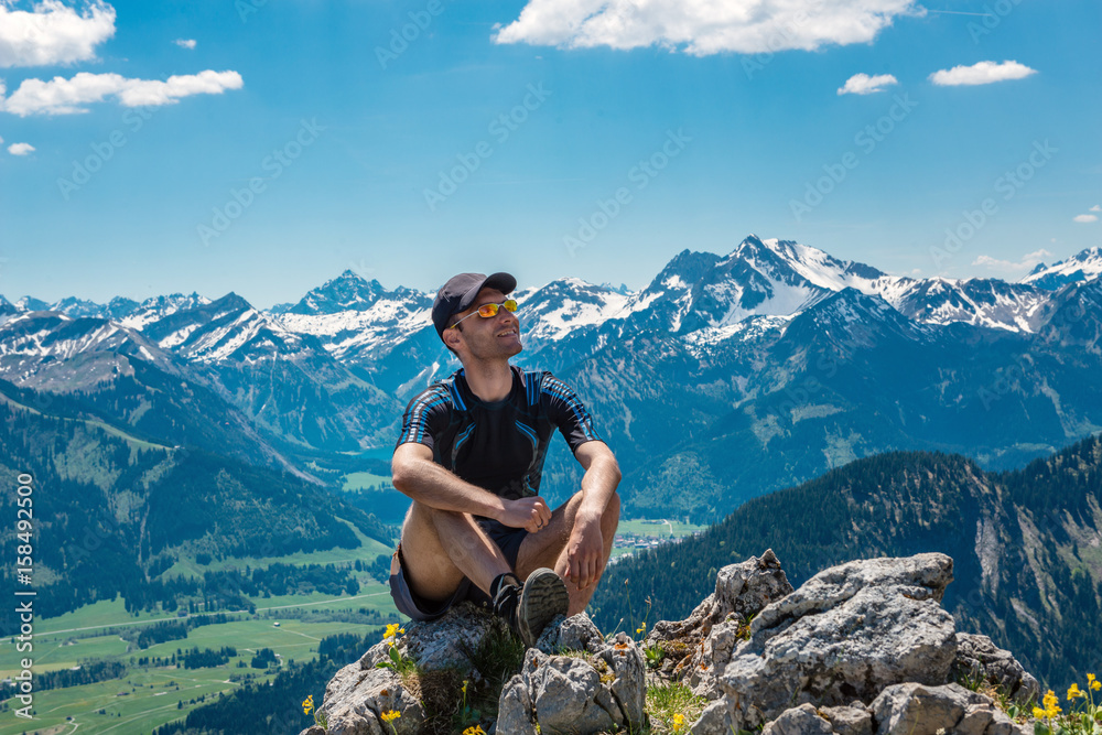 Naklejka premium Happy man sitting on a rock in mountains