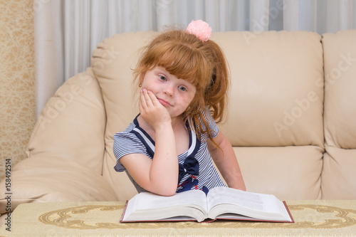 The little girl at the table with an open book