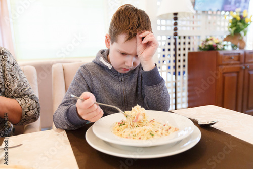 Preteen handsome boy with a plate of pasta refuse to eat