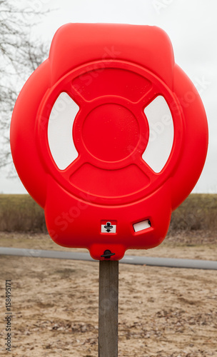 Bright red lifebuoy case on wooden pole