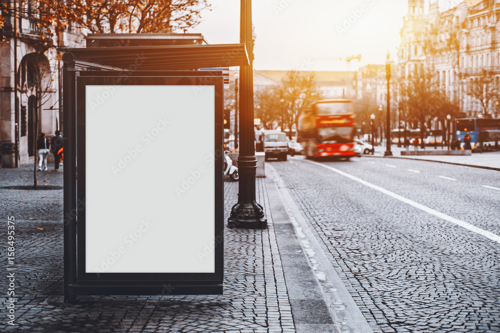 White empty information mock-up on city bus stop, blank vertical billboard near paved road with red touristic bus, clear placeholder frame in urban settings with copy space for text or advertising