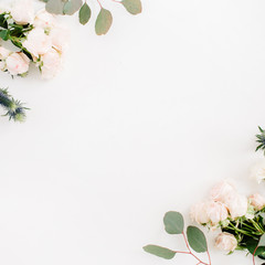 Border frame made of beige rose flowers, eringium flower, eucalyptus branches on white background. Flat lay, top view. Floral background