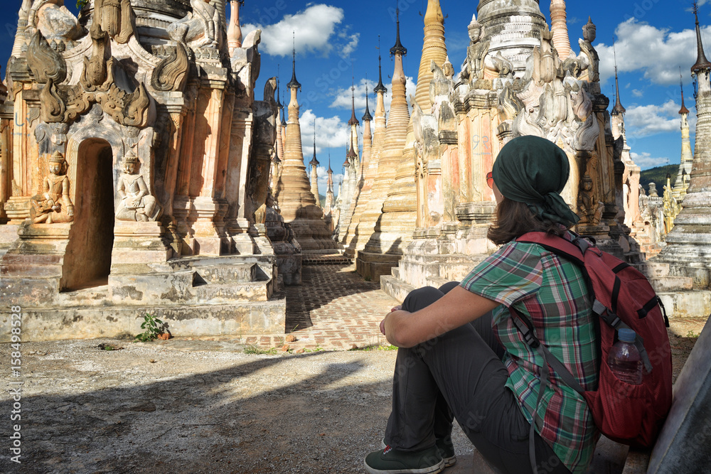 Hiker with backpack sit and look Buddhist stupas in Burma