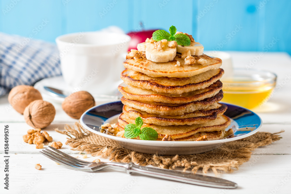 Pancakes with banana, honey, walnuts and mint on plate. Pancakes with banana, honey, walnuts and mint on plate.