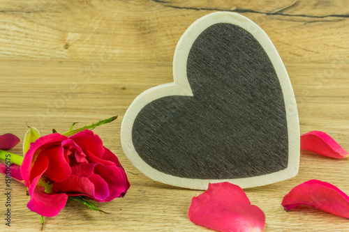 A heart with red roses on a rustic wooden table photo