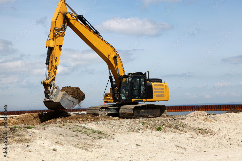 Excavator works on a construction site with excavation Excavator works on a construction site with excavation