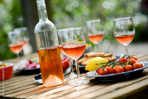 holiday summer brunch party table outdoor in a house backyard with appetizer, glass of rosé wine, fresh drink and organic vegetables
