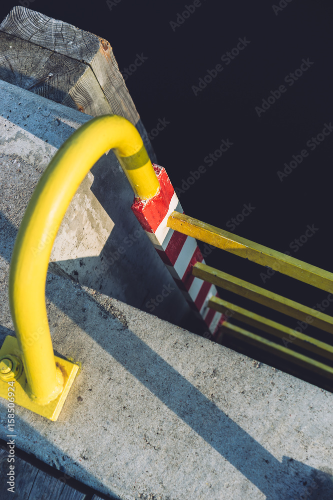 Old yellow ladder on a pier, leading to the sea Old yellow ladder on a pier, leading to the sea