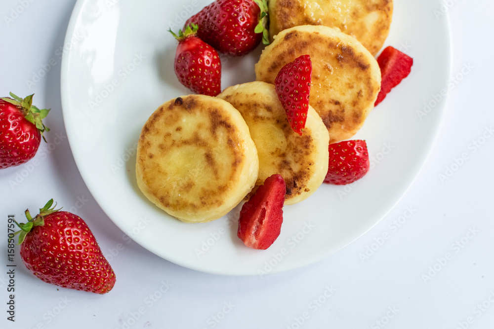 Delicious curd fritters with strawberry on a white plate Delicious curd fritters with strawberry on a white plate
