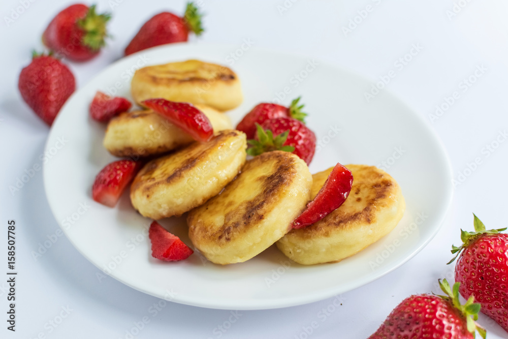 Delicious curd fritters with strawberry on a white plate Delicious curd fritters with strawberry on a white plate