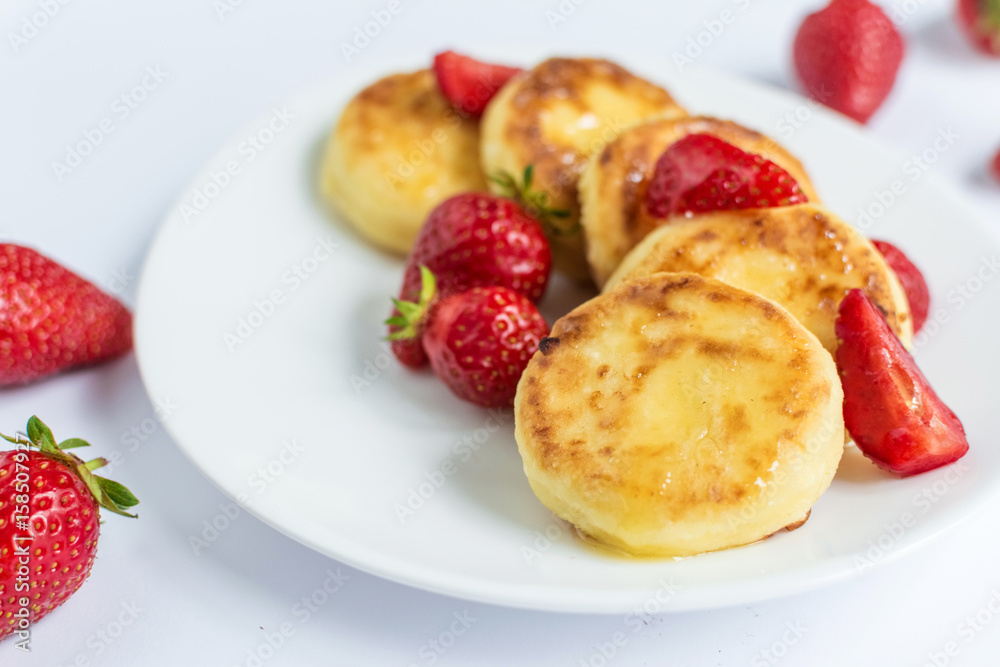 Delicious curd fritters with strawberry on a white plate Delicious curd fritters with strawberry on a white plate