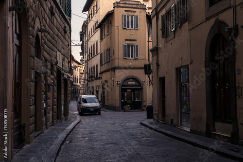 Fototapeta Naklejka Na Ścianę i Meble -  Narrow street and buildings with parked white van in Florence Italy, at dawn.