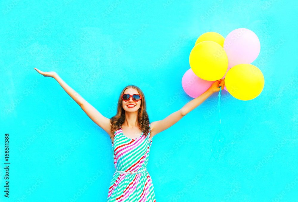 happy smiling woman and an air colorful balloons is having fun on a blue background - obrazy, fototapety, plakaty 